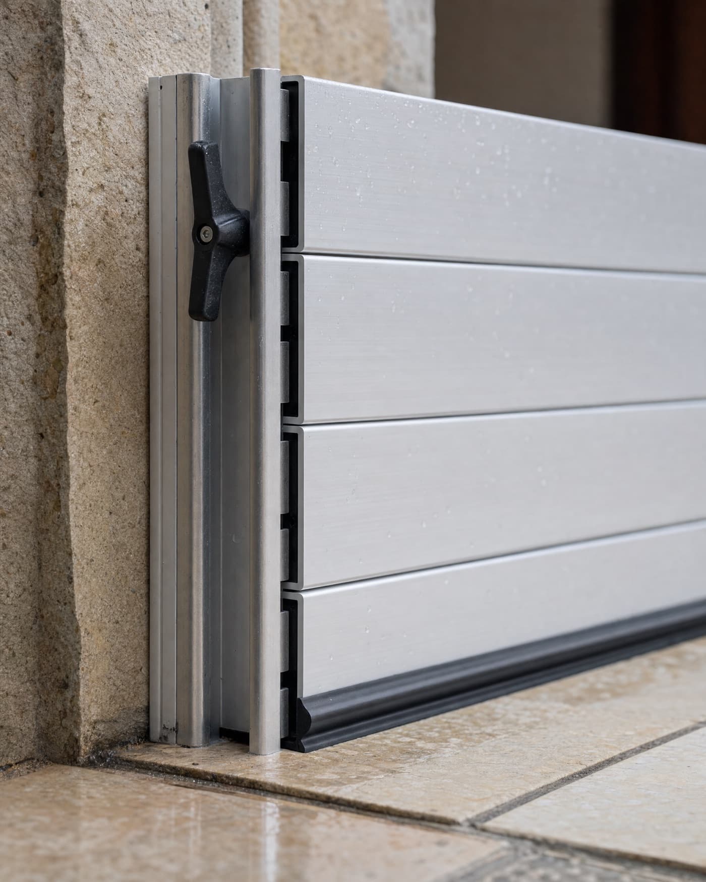 Detalle de la guía lateral, la maneta de apriete y la junta de goma de una barrera de aluminio.